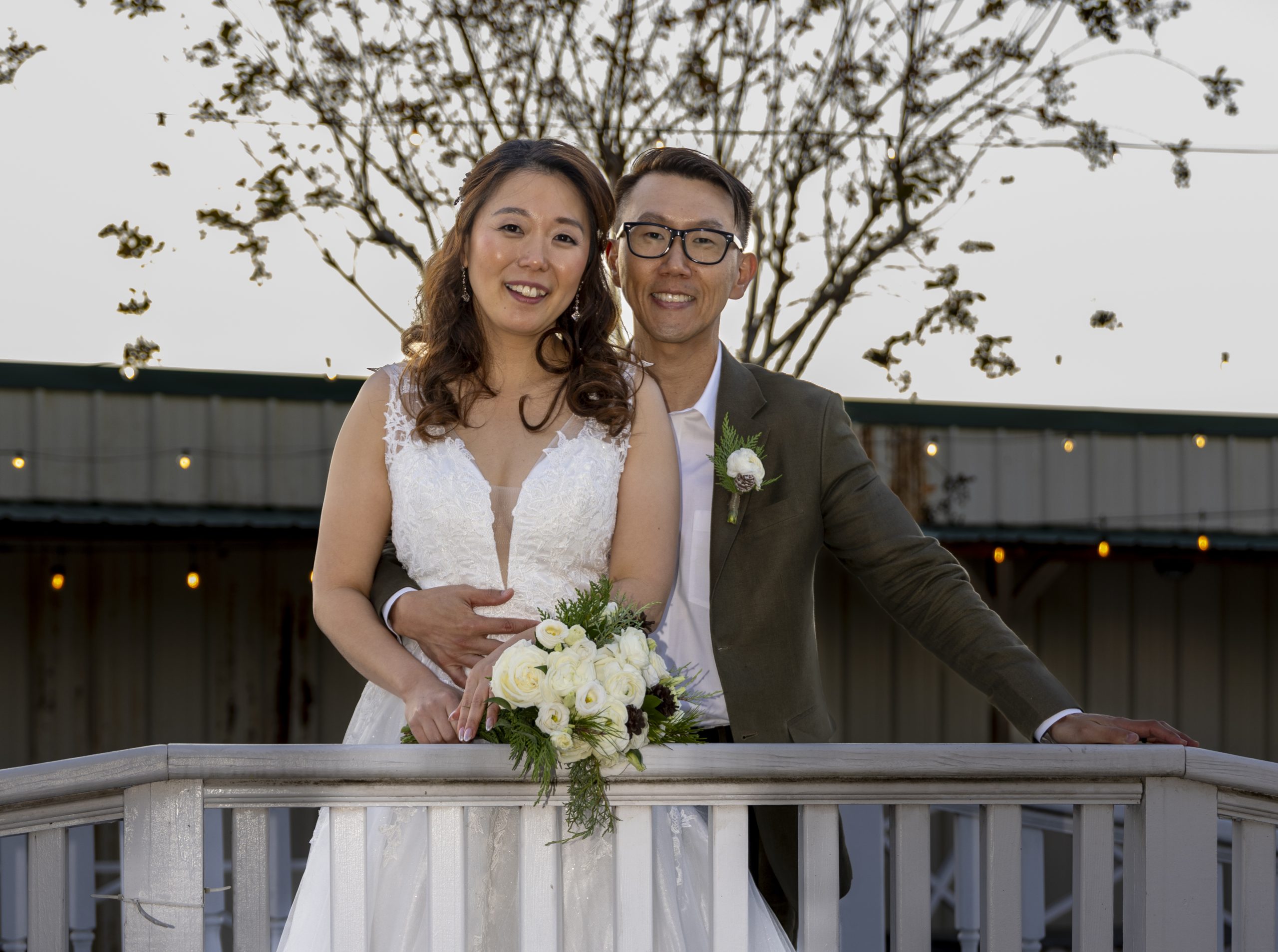 First Reflections An Asian couple poses on a wooden bridge after their wedding ceremony.